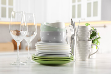 Many different clean dishware, glasses, cups and cutlery on white marble table indoors