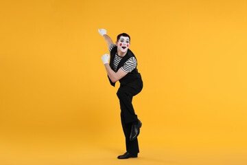 Funny mime artist posing on orange background