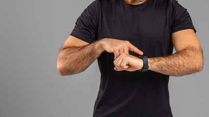 Man Checking Time on Wristwatch Against Gray Background