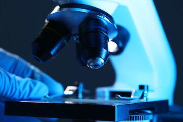 Scientist with microscope on dark blue background, closeup
