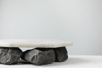 Presentation for product. Marble podium and stones on grey background. Space for text