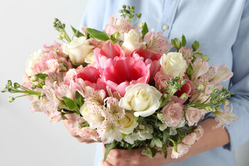 Woman with beautiful bouquet of fresh flowers on light background, closeup
