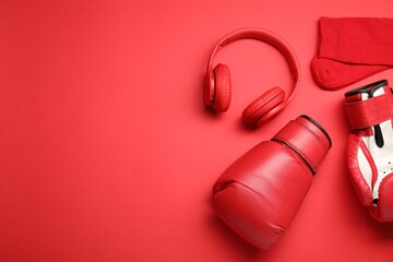 Sports equipment. Boxing gloves, headphones and socks on red background, flat lay. Space for text