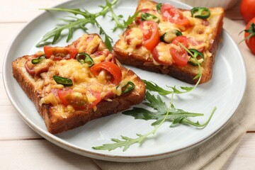 Obraz premium Tasty pizza toasts and fresh arugula on light wooden table, closeup