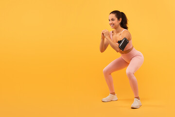 Young Woman Performing Squats Against a Vibrant Yellow Background