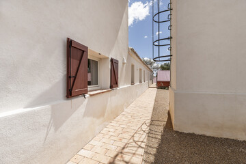 A long perimeter hallway in a country house with white facades, red wooden shutters and terracotta...