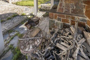 A pile of dry firewood next to a grill