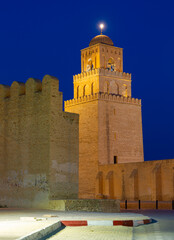 Evening view of unique medieval three tapering level minaret topped with small ribbed dome of Great Mosque of Kairouan, Tunisia