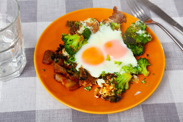 Appetizing breakfast - scrambled eggs with fried lard and broccoli