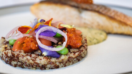 An appetising Quinoa meals with salmon, sauce and toppings.