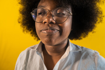 mujer joven afro usando lentes y haciendo un mal gesto en su rostro mientras usa su cabello suelto 