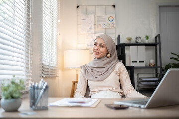 Muslim businesswoman working using laptop and taking notes on documents In the modern office