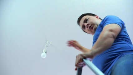 Happy man fixes electricity in house and suddenly fall from ladder. Man changes lamp in ceiling with easy proofs good abilities of owner - Powered by Adobe
