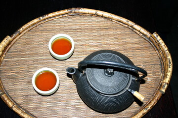 Black iron tea pot with tea cups on bamboo tray 