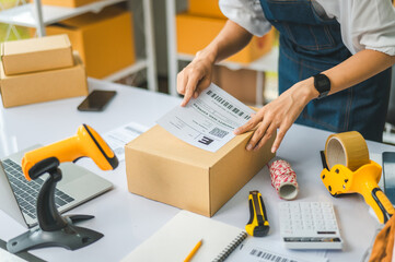 startup young female small business owners attaching shipping labels to cardboard boxes or parcels...