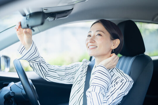 車内のミラーを見ながら髪の毛をなおす女性