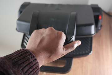 Hand using finger to press button on grill gadget