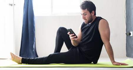 Joven apuesto en casa usando el teléfono celular