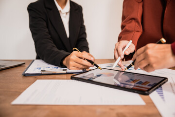 Diverse group of professionals businesswomen gather in meeting room for collaborative discussions on finance, strategy, and teamwork, technology tablets and laptops for data analysis and presentation