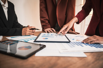 Diverse group of professionals businesswomen gather in meeting room for collaborative discussions on finance, strategy, and teamwork, technology tablets and laptops for data analysis and presentation