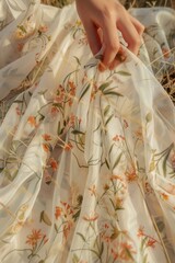 Close-up of a delicate floral pattern on a flowing sundress, fingers gently tracing the textured fabric