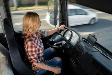 Young woman truck driver, driving truck on the highway, cars in motion 