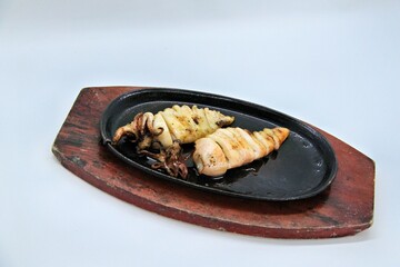 Grilled squids or 'Cumi Bakar' is a sweet and tangy seafood dish that is often sold as street food in Indonesia. It is marinated in sweet soy sauce and a mixture of spices before being grilled. 