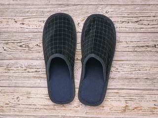Comfortable men's slippers on a wooden background.