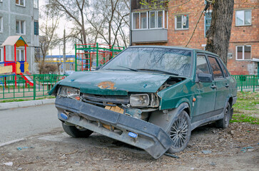 A car destroyed in an accident is abandoned in the courtyard of a residential building