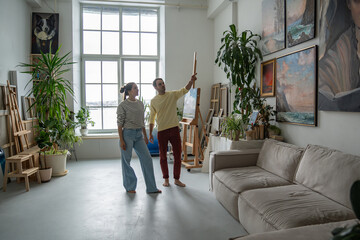 Professional painter guy girl during workflow in light spacious art studio in loft style. Work...
