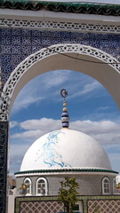 White dome visible through a blue, tiled arch on the roof of a carpet shop in Kairouan, Tunisia