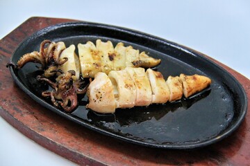 Grilled squids or 'Cumi Bakar' is a sweet and tangy seafood dish that is often sold as street food in Indonesia. It is marinated in sweet soy sauce and a mixture of spices before being grilled. 