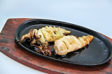 Grilled squids or 'Cumi Bakar' is a sweet and tangy seafood dish that is often sold as street food in Indonesia. It is marinated in sweet soy sauce and a mixture of spices before being grilled. 