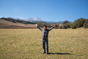 Joyous traveler celebrating in front of snowy volcano