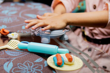 A child is playing with a toy kitchen set, including a spatula and a rolling pin