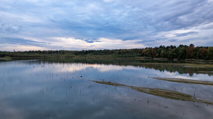 The image conveys a moment of tranquility at dusk with a view across a calm lake reflecting the...