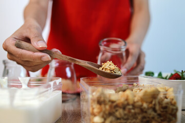 Hand Adding Oatmeal Into The Jar For Making Fresh Strawberry Parfait for Healthy Breakfast 