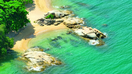 A serene aerial view of a tropical beach, where the emerald waters merge seamlessly with the...