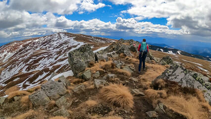 Woman walking next to path mark with Austrian flag painted on rock on remote alpine meadow near...
