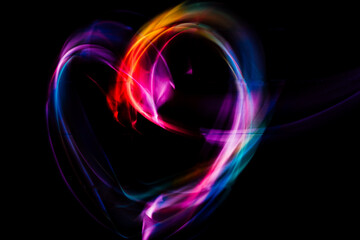 Light colorful heart shape on black background. Long exposure. Light painting photography.