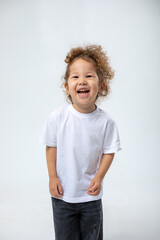 Curly mischievous girl, rejoicing, smiling, looking at the camera, in dark jeans posing on a white...