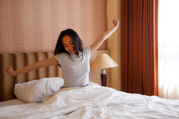 Asian Woman stretching hands in bed after wake up in the morning