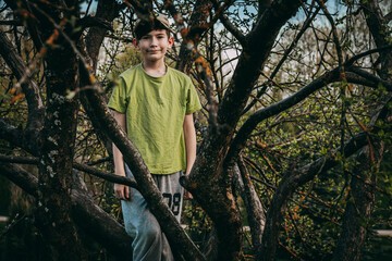 Portrait of a boy sitting on a tree branch in the garden
