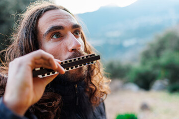 the musician enjoys playing the harmonica while standing on the street.