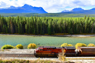 Long freight train moving along Bow river in Canadian Rockies ,Banff National Park, Canadian...