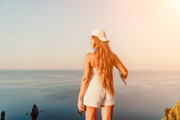 A female tourist stands by the sea wearing a white cap and T-shirt, looking happy and relaxed.