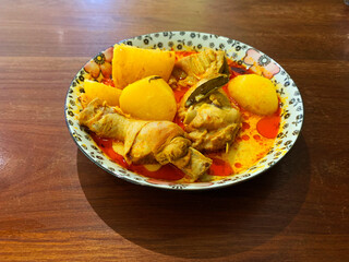 signature Malay nonya spicy chilli curry leaf chicken and potato in plate on wood table asian halal food restaurant banquet cuisine menu for cafe design