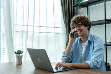 Caucasian young businessman talking on phone while working from home. 