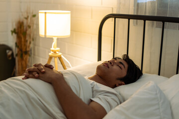 Asian attractive man lying down on bed in bedroom, dreaming at night. 