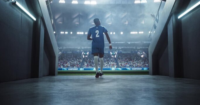 African American Footballer in a Blue Uniform Walking Out of the Tunnel onto the Sports Stadium Field. MVP Forward Player Entering a Crowded Arena Full of Soccer Spectators